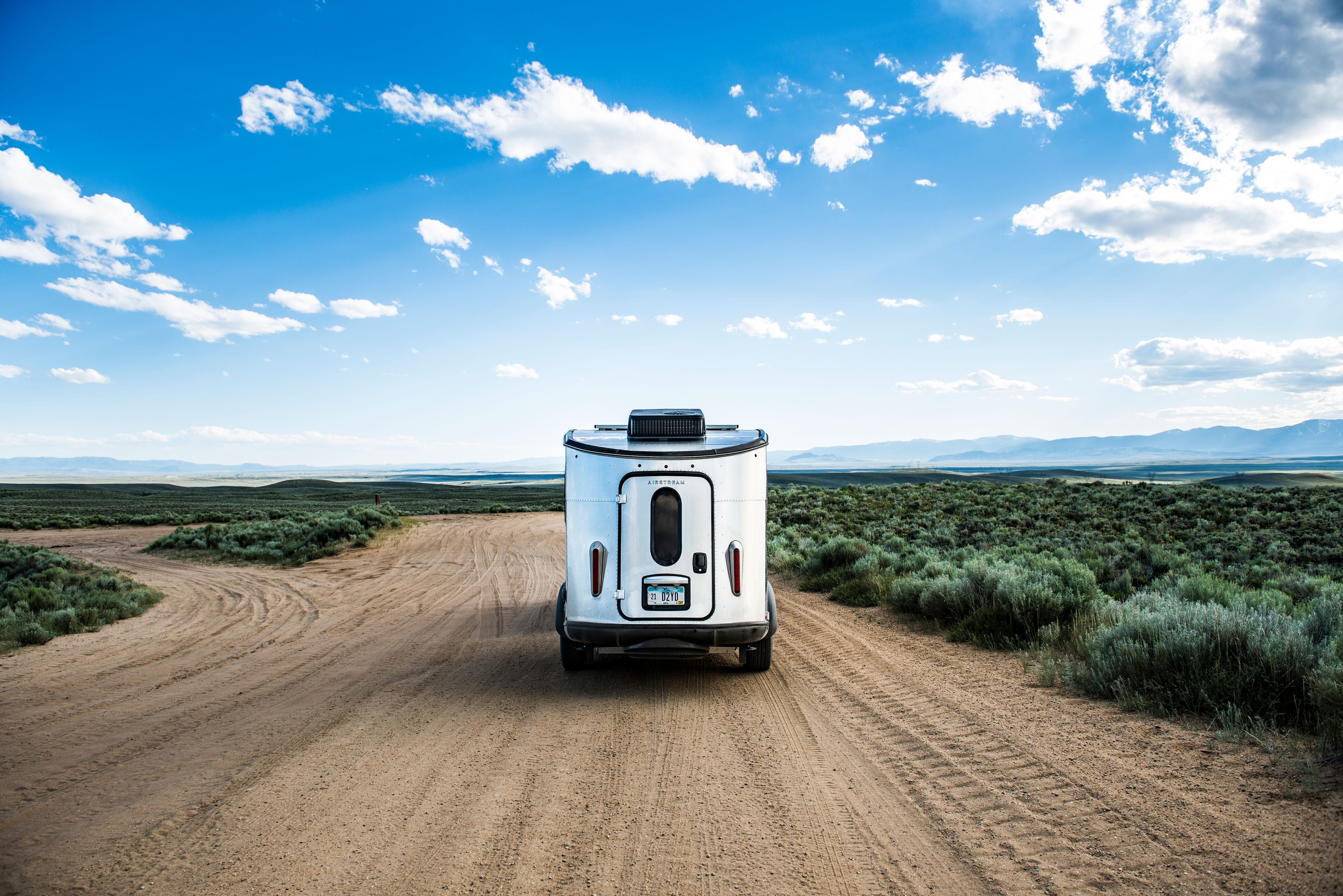 Airstream Basecamp on a dirt road being towed by an SUV.