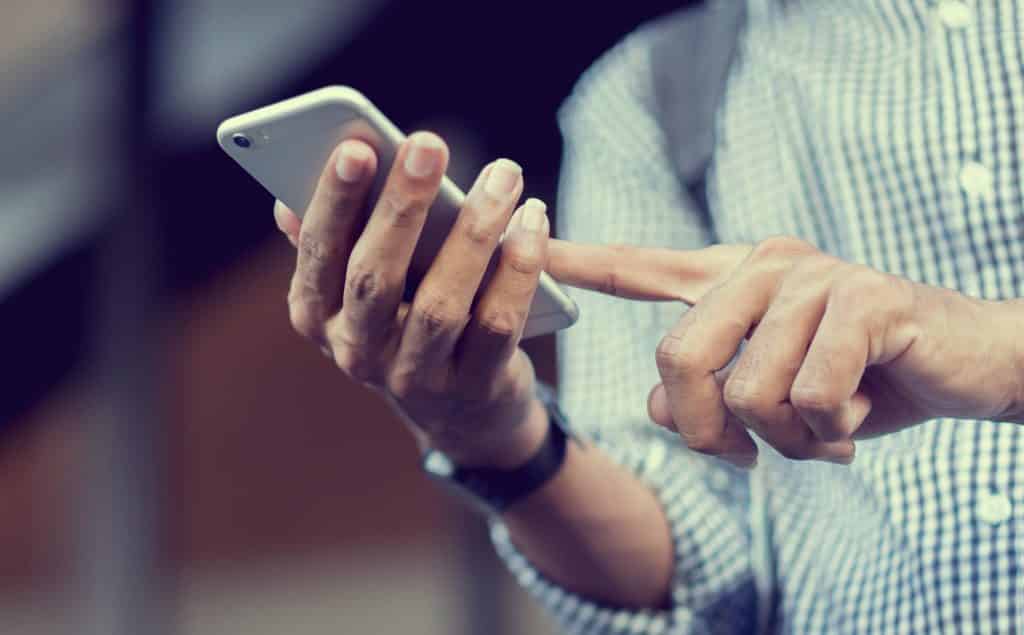 close up traveler backpacker man hand holding smartphone for checking flight online or search information on browser website about plan trip at destination , lifestyle concept